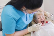 Дівчина в стоматологічному кріслі, рот відкритий, має огляд зубів — стокове фото