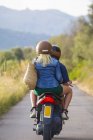 Visão traseira do jovem casal equitação ciclomotor na estrada rural — Fotografia de Stock