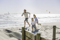 Отец и дети бегают по пляжу — стоковое фото