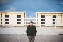 Retrato de hombre adulto medio frente a cabañas de playa, Sorso, Sassari, Cerdeña, Italia - foto de stock
