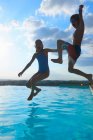 Ragazza e fratello che saltano in piscina, Buonconvento, Toscana, Italia — Foto stock