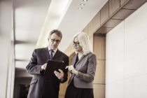 Businesswoman and man using digital tablet in office corridor — Stock Photo