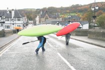 Dos kayakistas que llevan kayaks en el puente sobre el río Dee, Llangollen, Gales del Norte - foto de stock