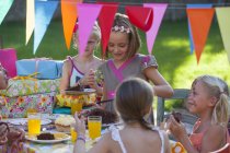 Chica sirviendo amigos pastel de cumpleaños en la fiesta - foto de stock