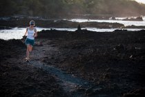 Жінка біжить на кам'янистому пляжі — стокове фото