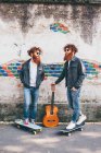 Молоді чоловічі хіпстерські близнюки з рудим волоссям і бородою на тротуарі зі скейтбордами — стокове фото