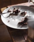 Leftover crumbs of chocolate pie with spoon on plate — Stock Photo