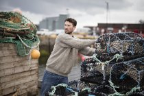 Jovem pescador empilhando panelas de lagosta no porto, Fraserburgh, Escócia — Fotografia de Stock