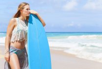 Junge Frau lehnt an Surfbrett am Strand, Dominikanische Republik, Karibik — Stockfoto