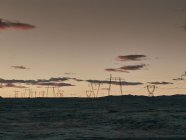 Електричні пілони в ландшафті з небом заходу сонця — стокове фото
