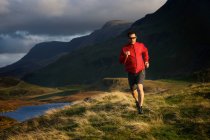 Escursionista che corre su una collina erbosa — Foto stock