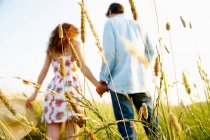 Vue arrière du couple tenant la main dans un champ de blé — Photo de stock
