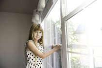 Jovem menina olhando para longe da janela — Fotografia de Stock