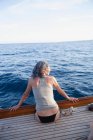 Mujer sentada en la baranda de un barco - foto de stock