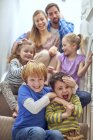 Happy parents and children sitting on staircase — Stock Photo
