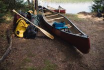 Canoa e equipamentos de acampamento ao lado do lago — Fotografia de Stock