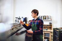 Profile shot of young craftsman looking at metal letterpress spacing in a book arts workshop — Stock Photo