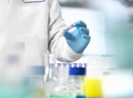 Обрезанное изображение ученого, держащего образец во флаконе эндорфина во время эксперимента в лаборатории — стоковое фото