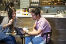 Junges Paar schaut im Café auf digitales Tablet — Stockfoto