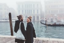 Vista trasera de la pareja en la costa del canal brumoso, Venecia, Italia - foto de stock