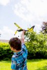 Ragazzo che gioca con aeroplano giocattolo all'aperto — Foto stock