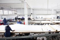 Женщины-работники фабрики разворачивают текстиль на швейной фабрике — стоковое фото