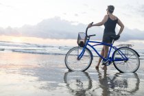 Frau mit Fahrrad am Strand bei Sonnenuntergang, nosara, guanacaste provinz, costa rica — Stockfoto