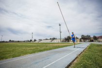 Bóveda de poste macho joven corriendo con bóveda de poste en instalaciones deportivas - foto de stock