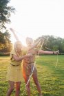 Дві молоді жінки друзі, загорнувшись у стримери на вечірці в парку — стокове фото