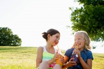Rindo meninas beber suco ao ar livre — Fotografia de Stock