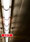 Sinal de saída e luzes fluorescentes no teto — Fotografia de Stock