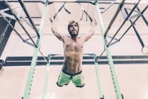 Vue à faible angle de la formation des jeunes hommes cross-trainer sur les anneaux d'exercice dans la salle de gym — Photo de stock