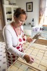 Зрелая женщина наносит сушеную лаванду на мыло в мыльной мастерской ручной работы — стоковое фото