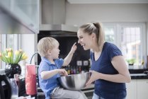 Mother and son fooling around whilst baking, son putting mixture on mother's nose — Stock Photo