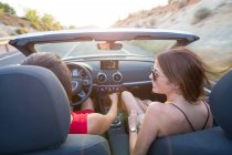 Rückansicht zweier junger Frauen, die im Cabrio auf einer Landstraße fahren, Mallorca, Spanien — Stockfoto