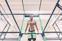 Vue à faible angle de la formation de jeunes hommes cross-trainer sur barre d'exercice dans la salle de gym — Photo de stock