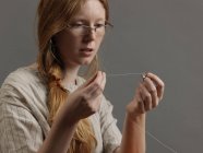 Молодая дизайнер нанизывает нитку на иглу — стоковое фото