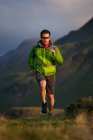 Escursionista che corre in un campo erboso — Foto stock
