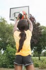 Donna che spara basket sul campo — Foto stock