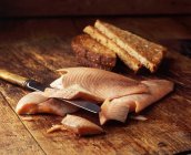 Копчений лосось зі скибочками цільного тосту на дерев'яному столі — стокове фото