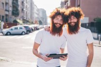Portrait of young male hipster twins with red hair and beards on city street — Stock Photo