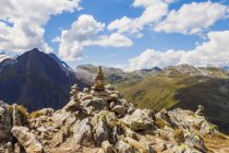 Stack of rocks with mountain landscape in sunlight — Stock Photo
