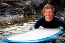Hombre acostado en la tabla de surf en el agua - foto de stock