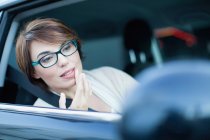 Frau überprüft Make-up im Seitenspiegel — Stockfoto