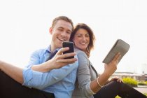 Casal usando telefone inteligente e tablet digital — Fotografia de Stock