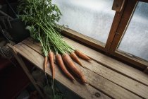 Bunch of freshly harvested carrots on wood — Stock Photo