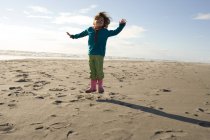 Молодая девушка прыгает по песчаному пляжу — стоковое фото