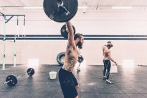 Young male cross trainer snatch lifting barbell in gym — Stock Photo