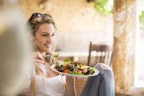 Young woman relaxing on garden patio eating salad — Stock Photo