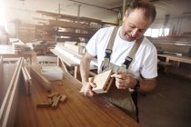 Человек плотник вставляет деревянный штифт на верстак — стоковое фото
